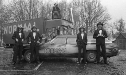 Foto van de band Normaal bij een vrachtwagen en Chevrolet. Fotograaf Hugo Jaartsveld. Bron ECAL